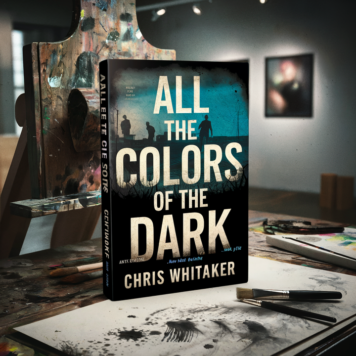 A book titled "All the Colors of the Dark" by Chris Whitaker on an artist's workspace.