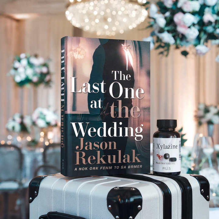 A book titled "The Last One at the Wedding" by Jason Rekulak is displayed on a suitcase.